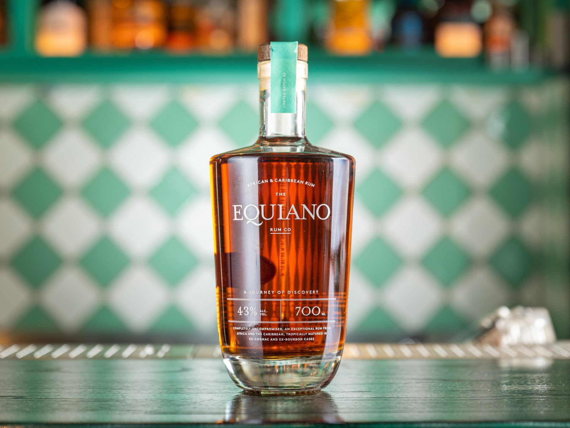 Bottle of Equiano Original with green and white bar decor in background