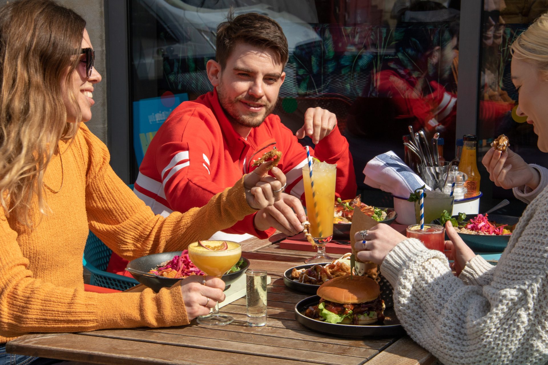 Guests with food and cocktails outside in the sunshine