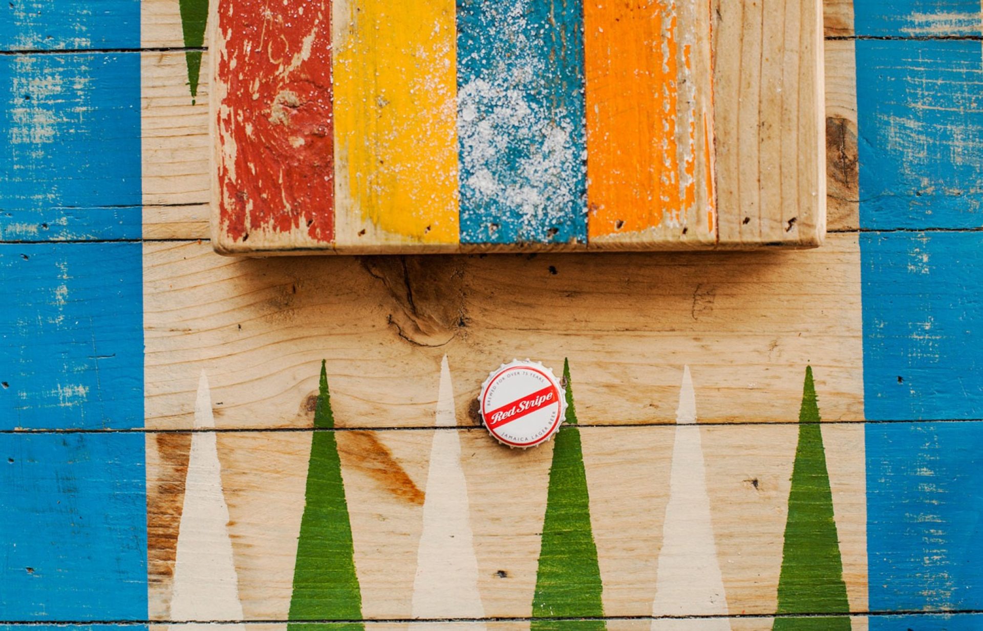 Staines Turtle Bay Red Stripe bottlecap on colourful table