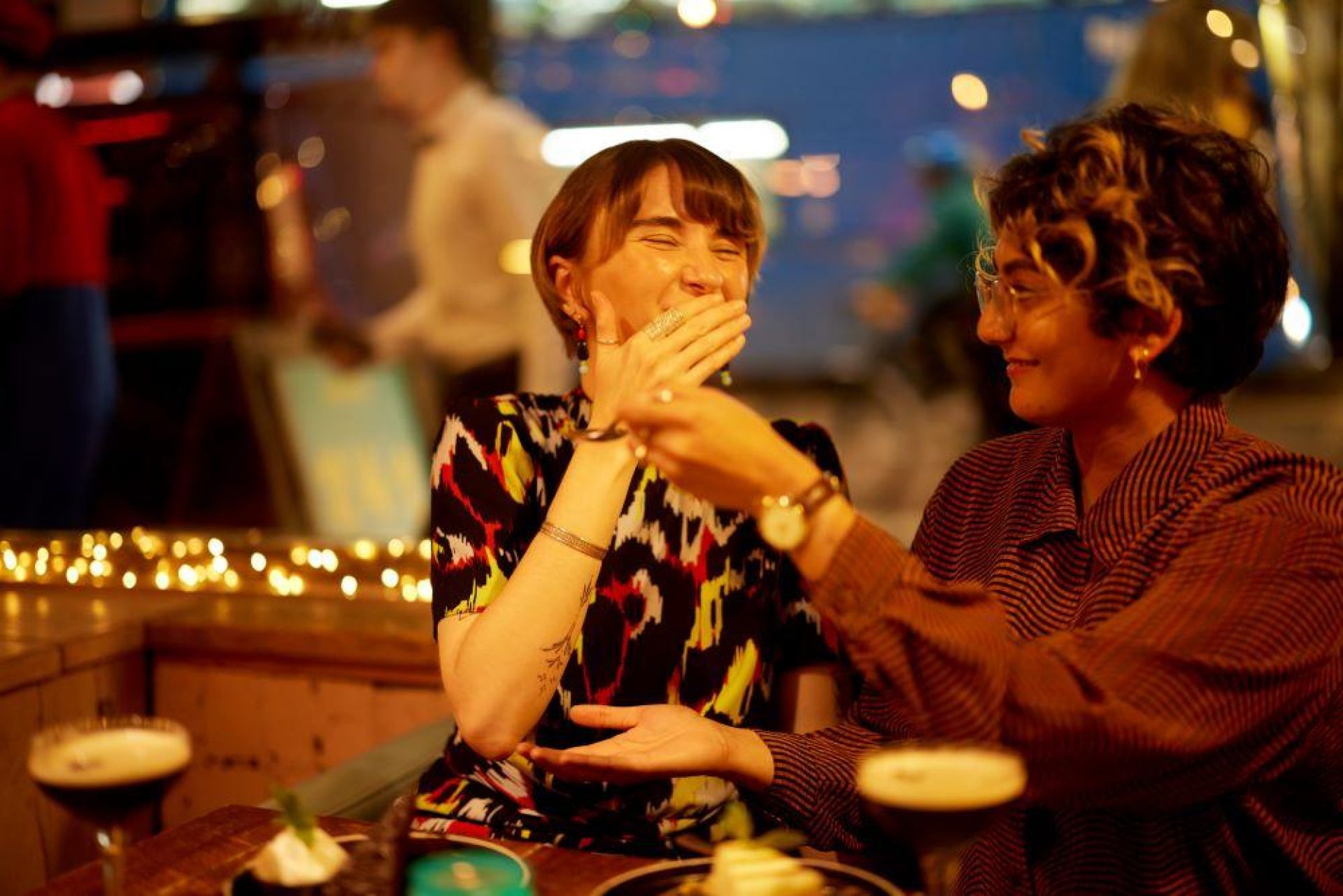 Sharing a cheesecake with cocktails window and fairy lights background 3 2