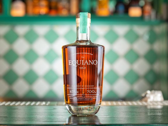 Bottle of Equiano Original with green and white bar decor in background